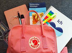 Lehrbuch, Kalender, Tablet, Stifte und ein Block finden sich im Rucksack vieler Studenten.